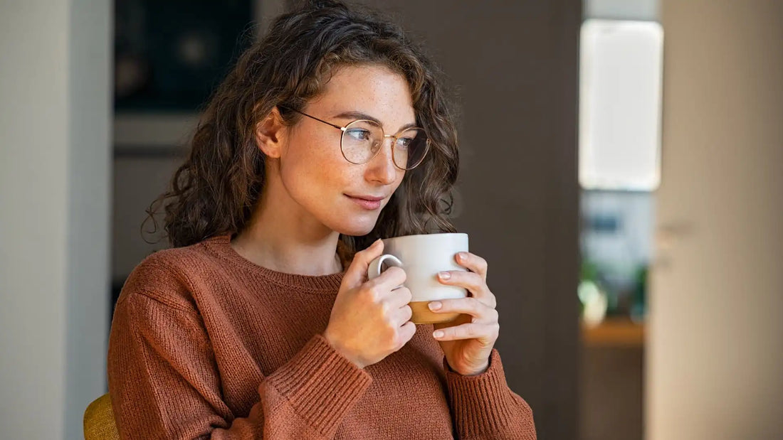Does tea break a fast? A woman in a brown sweater holding a mug full of tea.