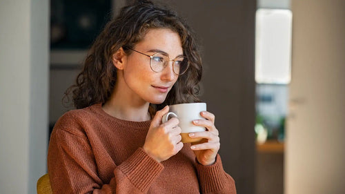 Does tea break a fast? A woman in a brown sweater holding a mug full of tea.