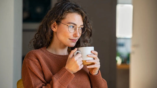 Does tea break a fast? A woman in a brown sweater holding a mug full of tea.