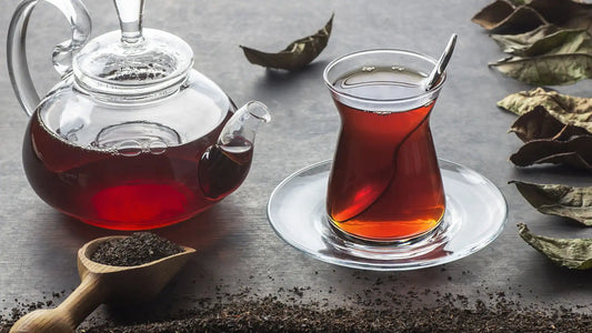 Does black tea have caffeine? A pot of black tea on a tabletop scattered with loose leaf black tea.